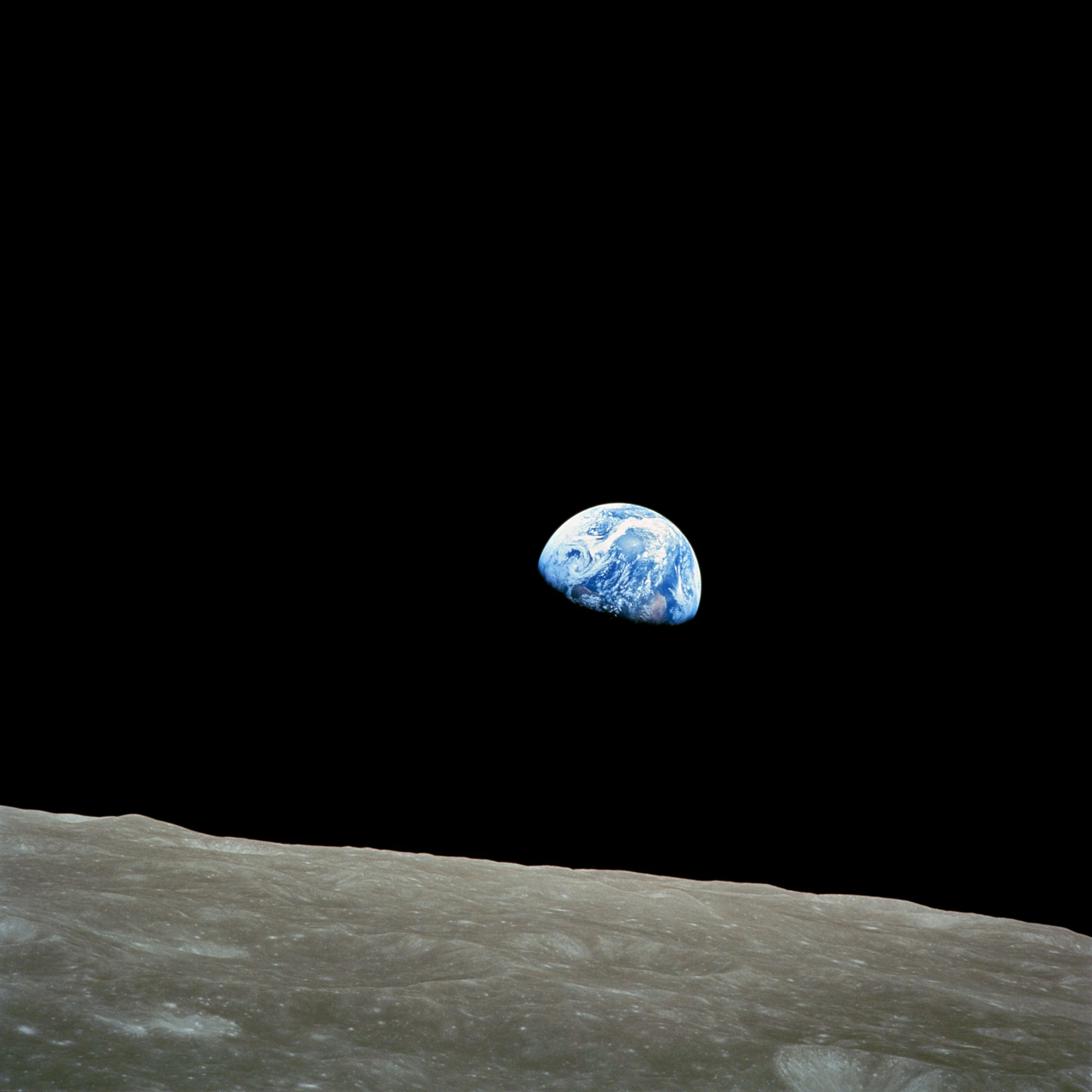 La Tierra azul se eleva sobre el horizonte gris de la Luna contra el espacio negro.